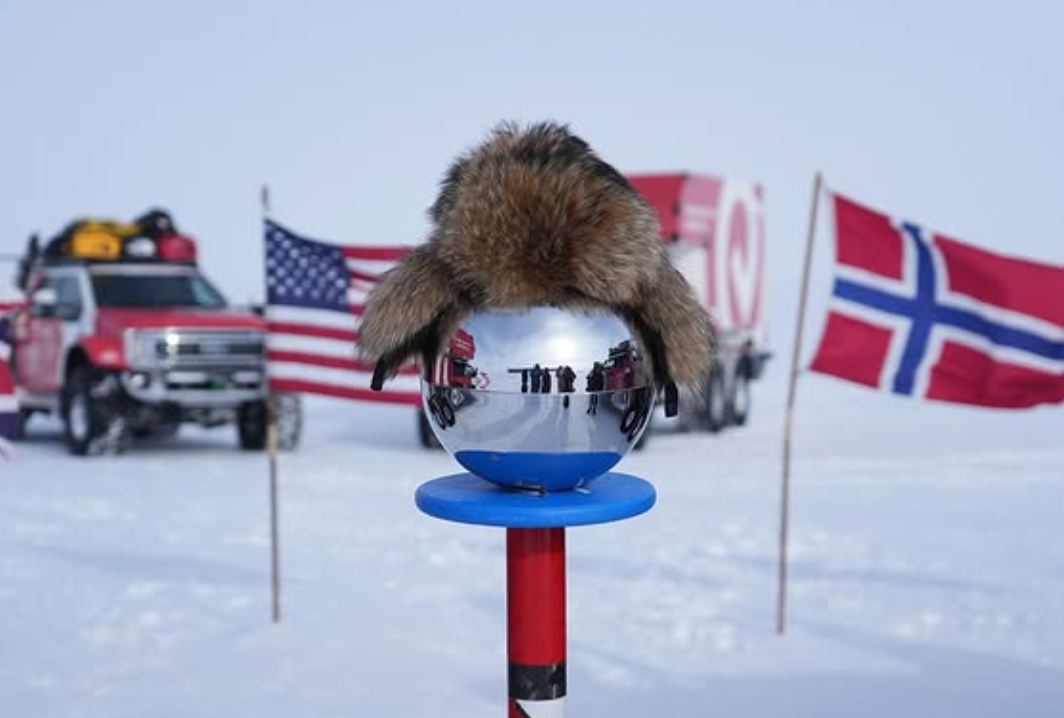 The South Pole is pictured with a fuzzy hat on it and a Ford Super Duty truck parked behind. 